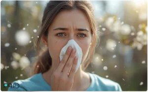 دختری در فضای باز با دستمال جلوی بینی در میان ذرات گرده گل، نشانه‌ای از آلرژی فصلی و حساسیت تنفسی.