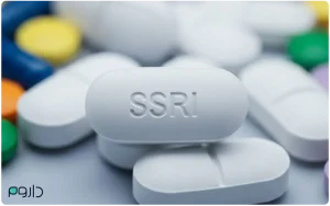 قرص سفید با نوشته SSRI در میان چند قرص رنگی؛ نمادی از داروهای ضدافسردگی مهارکننده بازجذب سروتونین.