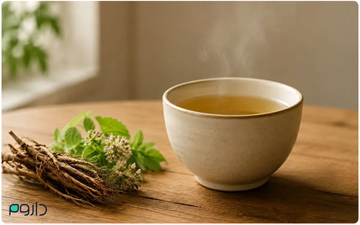 دمنوش سنبل‌الطیب همراه با ریشه و برگ تازه روی میز چوبی.