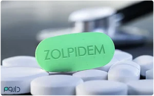 نمای نزدیک از قرص زولپیدم در کنار قرص‌های دیگر و گوشی پزشکی، برای معرفی این داروی خواب‌آور.